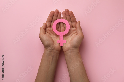 Woman holding female gender sign on pink background, top view photo
