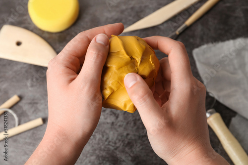 Woman holding clay over grey stone table with modeling tools, closeup photo