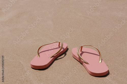 Stylish pink flip flops on wet sand. Space for text