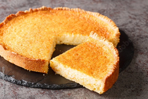One of the creamiest mixtures of gooey sour and sweet, this Southern buttermilk pie closeup in a slate plate on the table. Horizontal