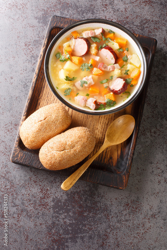 Split pea soup with potato, onion, carrot, bacon and sausages close-up in a bowl on the table. Vertical top view from above photo