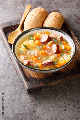 Split pea soup with potato, onion, carrot, bacon and sausages close-up in a bowl on the table. Vertical
