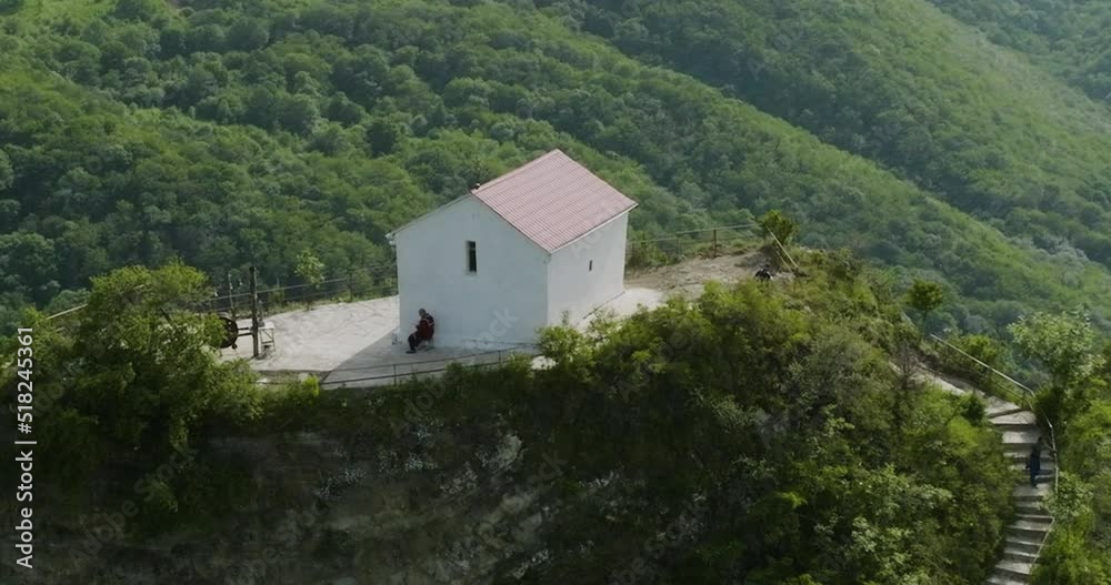 Secluded house in the wilderness, with a solitary person sitting nearby it. Secluded house in the wilderness, with a solitary person sitting nearby it.