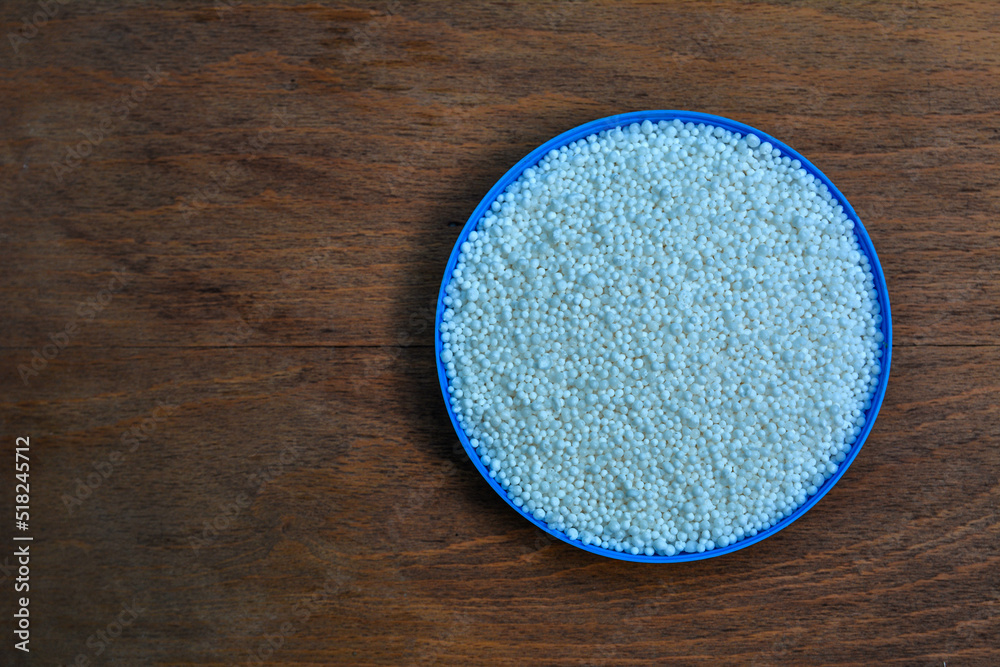Pellets of ammonium nitrate on wooden table, flat lay. Mineral fertilizer Pellets of ammonium nitrate on wooden table, flat lay. Mineral fertilizer