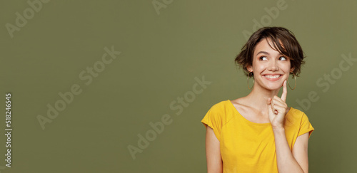 Young fun smiling pensive dreamful happy woman she 20s wear yellow t-shirt look aside on workspace area mock up isolated on plain olive green khaki background studio portrait People lifestyle concept