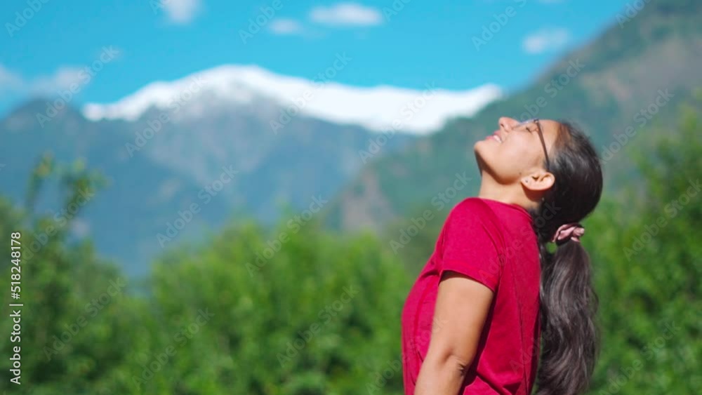 Indian Woman traveler with arms raised on mountain at Manali, Himachal Pradesh, India. Female enjoying holidays in mountains during summer. Watching beautiful mountain landscape in Manali.
