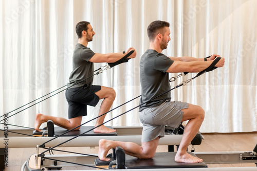 Men doing pilates exercise on reformer bed