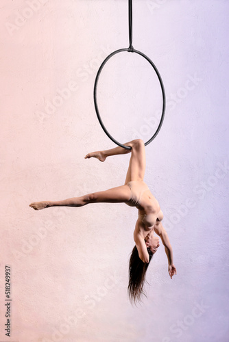 Flexible aerialist performing trick on aerial hoop