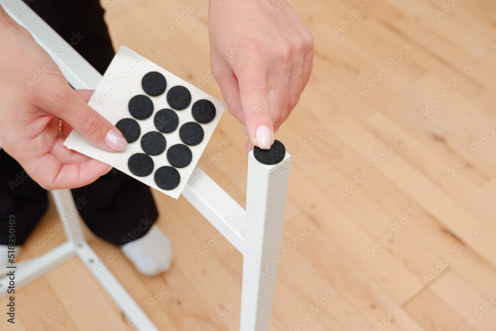 Antiskid felt pad cover install on wooden furniture leg. Woman attach