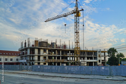 The big tower crane on building of shopping centre against the sky