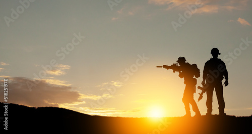 Silhouettes of soldiers standing against the backdrop of a sunset. Greeting card for Veterans Day, Memorial Day, Independence Day. USA celebration. Concept - patriotism, protection, remember honor.