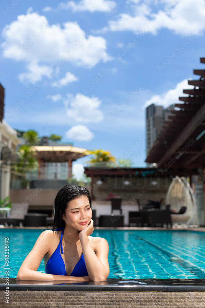 Young 20s Asian Woman feel happy in swimming pool with blue sky during holiday vacation