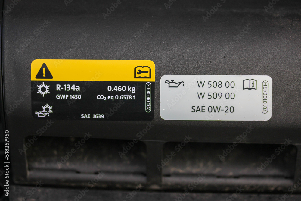 Air conditioning and oil warning labels under the hood of a new vehicle
