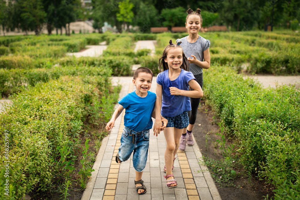 Three happy kids running in beautiful green park in summer