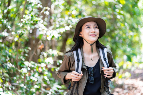 Asian young beautiful female backpacker traveling alone in forest wild. Attractive girl traveler look around and explore while walk in nature wood with happiness and fun during holiday vacation trip.
