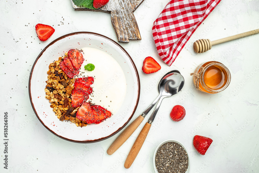Granola with yogurt with fresh strawberry, chia seeds and honey on a white background. Delicious balanced food concept. banner, menu, recipe place for text, top view