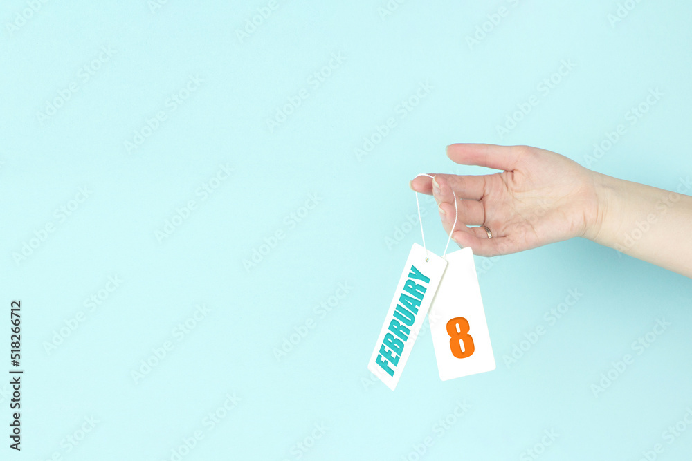 February 8th. Day 8 of month, Calendar date. Hand hold price tag with calendar date on blue background. Winter month, day of the year concept. February 8th. Day 8 of month, Calendar date. Hand hold price tag with calendar date on blue background. Winter month, day of the year concept.