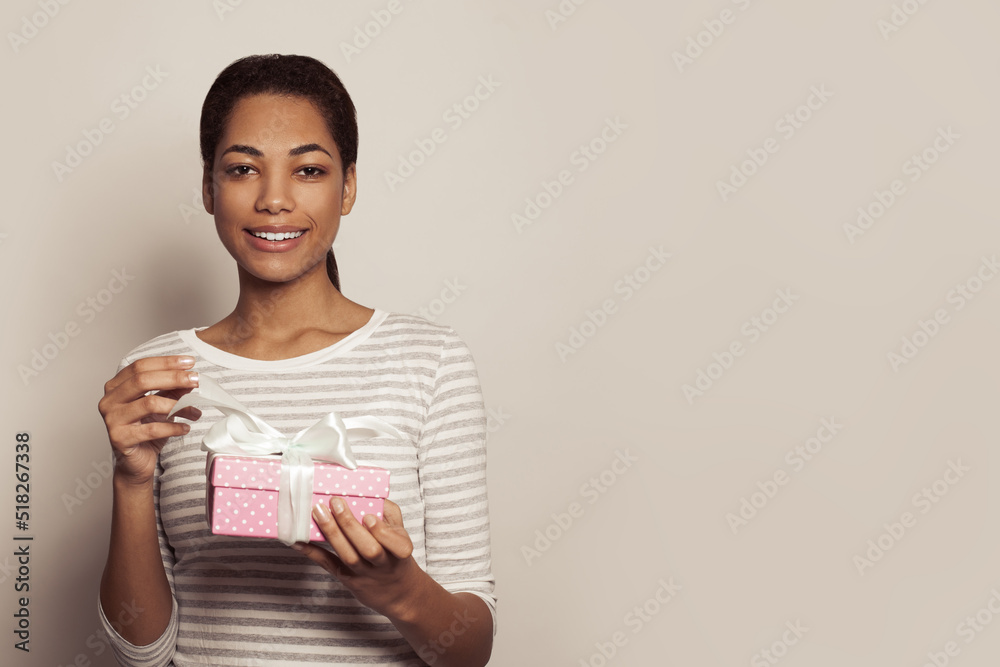 Pretty young black woman opening pink gift present box with white ribbon on white banner background Pretty young black woman opening pink gift present box with white ribbon on white banner background