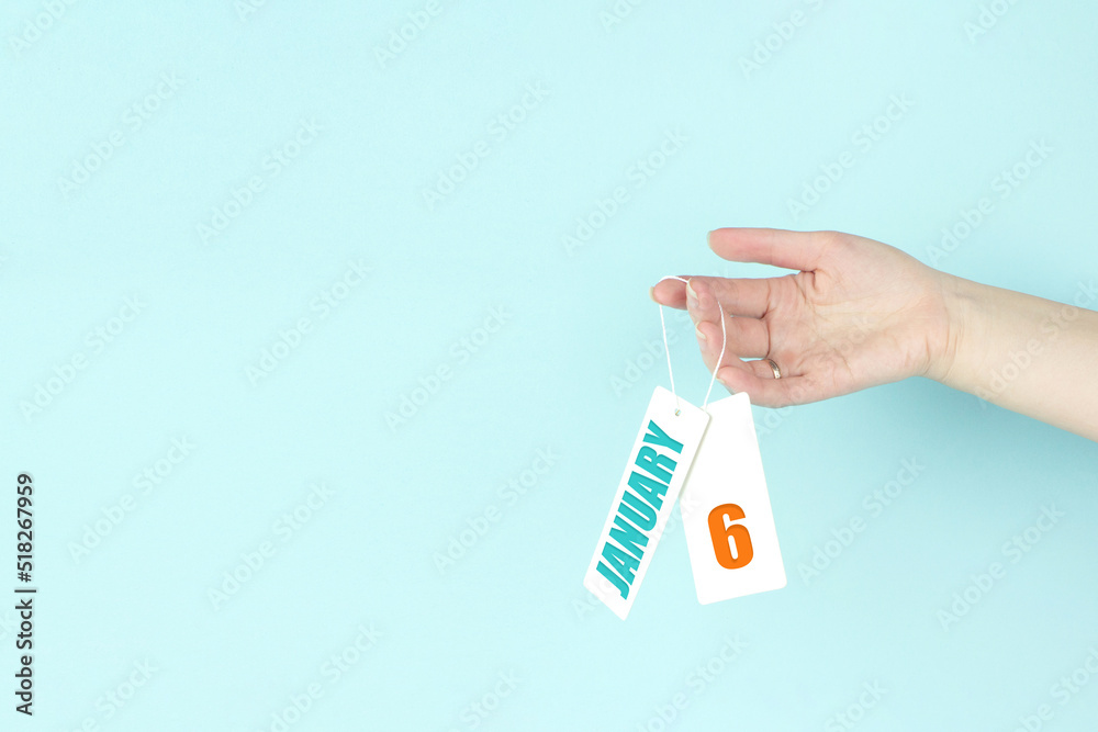 January 6th. Day 6 of month, Calendar date. Hand hold price tag with calendar date on blue background. Winter month, day of the year concept. January 6th. Day 6 of month, Calendar date. Hand hold price tag with calendar date on blue background. Winter month, day of the year concept.