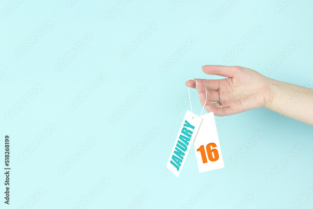 January 16th. Day 16 of month, Calendar date. Hand hold price tag with calendar date on blue background. Winter month, day of the year concept. January 16th. Day 16 of month, Calendar date. Hand hold price tag with calendar date on blue background. Winter month, day of the year concept.