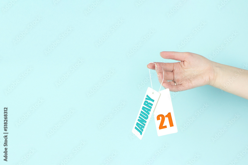 January 21st . Day 21 of month, Calendar date. Hand hold price tag with calendar date on blue background. Winter month, day of the year concept. January 21st . Day 21 of month, Calendar date. Hand hold price tag with calendar date on blue background. Winter month, day of the year concept.