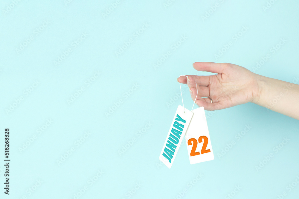January 22nd. Day 22 of month, Calendar date. Hand hold price tag with calendar date on blue background. Winter month, day of the year concept. January 22nd. Day 22 of month, Calendar date. Hand hold price tag with calendar date on blue background. Winter month, day of the year concept.