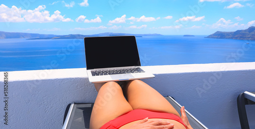 Cozy lifestyle with digital nomad freelancer woman in red bikini as running remotely with bright scenic view of the Mediterranean Sea ,Oia -Santorini,Greece