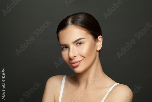 Attractive brunette woman with clean healthy skin looking at camera on black background