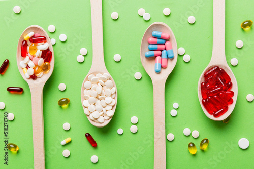 Vitamin capsules in a spoon on a colored background. Pills served as a healthy meal. Red soft gel vitamin supplement capsules on spoon © sosiukin