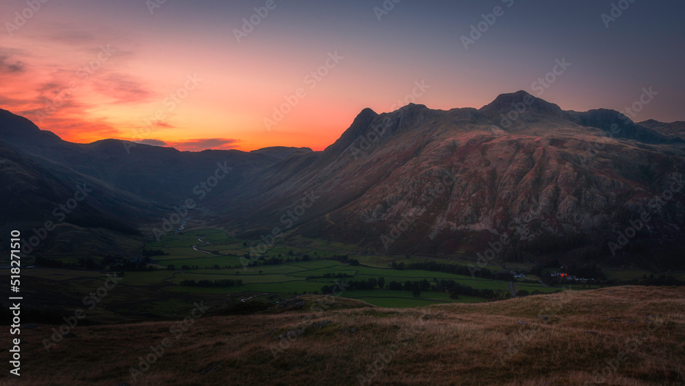 Sunset over Langdale Pikes in Lake District, UK. Beautiful evening landscape scene with the colourful sky over mountains.