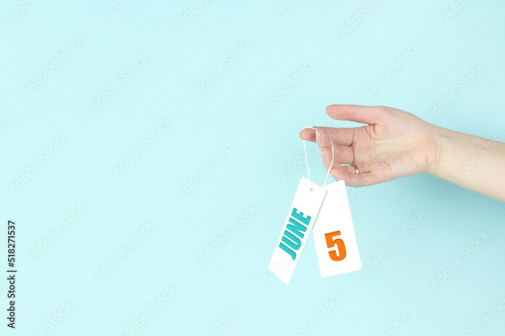 June 5th. Day 5 of month, Calendar date. Hand hold price tag with calendar date on blue background. Summer month, day of the year concept. June 5th. Day 5 of month, Calendar date. Hand hold price tag with calendar date on blue background. Summer month, day of the year concept.