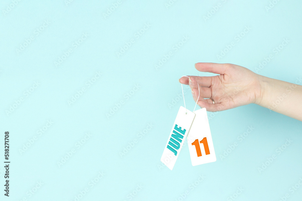 June 11st . Day 11 of month, Calendar date. Hand hold price tag with calendar date on blue background. Summer month, day of the year concept. June 11st . Day 11 of month, Calendar date. Hand hold price tag with calendar date on blue background. Summer month, day of the year concept.