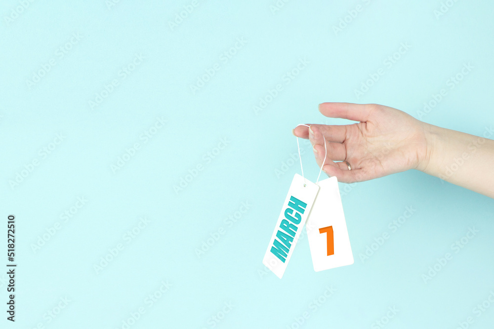 March 7th. Day 7 of month, Calendar date. Hand hold price tag with calendar date on blue background. Spring month, day of the year concept. March 7th. Day 7 of month, Calendar date. Hand hold price tag with calendar date on blue background. Spring month, day of the year concept.
