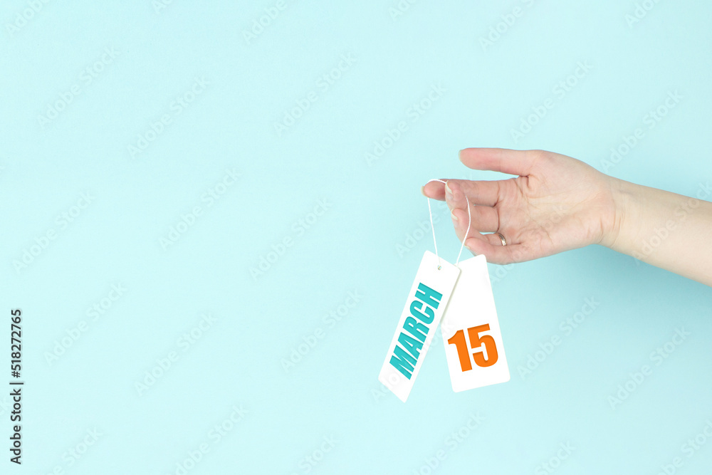 March 15th. Day 15 of month, Calendar date. Hand hold price tag with calendar date on blue background. Spring month, day of the year concept. March 15th. Day 15 of month, Calendar date. Hand hold price tag with calendar date on blue background. Spring month, day of the year concept.