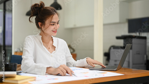 Beautiful young female economist working with document at her workplace