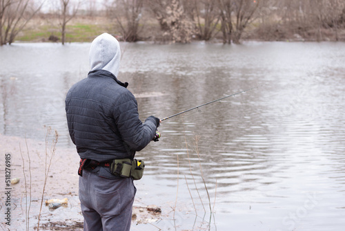 A geared up man fishing standing in the river or lake with a small fishing rod