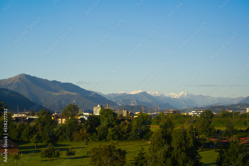Skyline of City of Baar and Zug with Swiss Alps in the background on a sunny summer day. Photo taken June 25th, 2022, Zug, Switzerland.