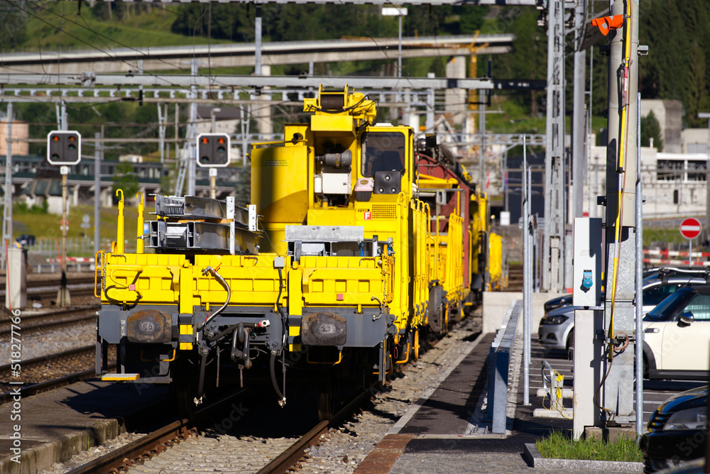 Railway station Airolo, Canton Ticino, with railway tracks and yellow construction train on a sunny summer day. Photo taken June 25th, 2022, Airolo, Switzerland. Railway station Airolo, Canton Ticino, with railway tracks and yellow construction train on a sunny summer day. Photo taken June 25th, 2022, Airolo, Switzerland.