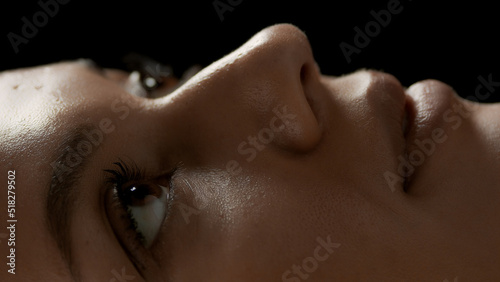 Big close-up shot of young good-looking African American female model s face on black background   Eyes care concept