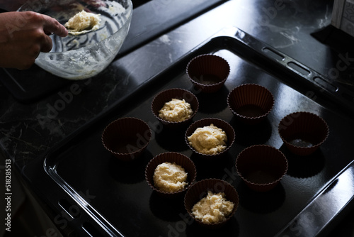woman housewife preparing muffins in silicone molds in her kitchen close-up
