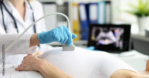 Doctor's hand with a probe on the belly of a pregnant woman photo