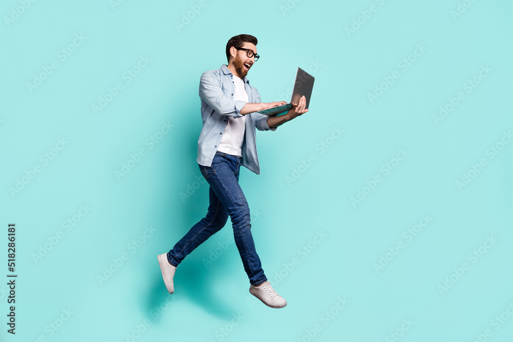 Full length portrait of active sporty person jump use wireless netbook isolated on turquoise color background