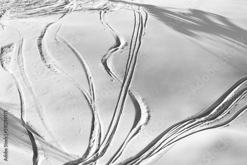 Black and white off-piste slope with track from ski and snowboard on sunny evening