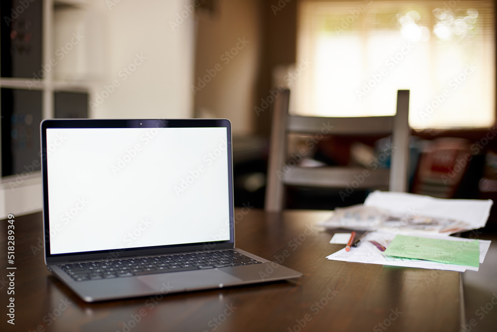 Mockup image of laptop with blank white desktop screen on a wooden table in an ordinary apartment. Business papers lie near the laptop in the home office. Laptop with blank screen for design. Mockup image of laptop with blank white desktop screen on a wooden table in an ordinary apartment. Business papers lie near the laptop in the home office. Laptop with blank screen for design.