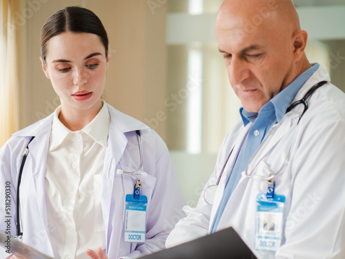 Selective focus at female doctor concentrate on consulting, discussing with male colleague in hospital. Two professional healthcare specialist standing in clinic brainstorming as medical teamwork.