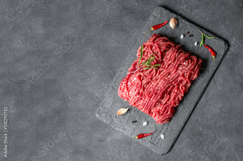 Raw minced meat on stone board with thyme, black peppers and garlic, butcher concept