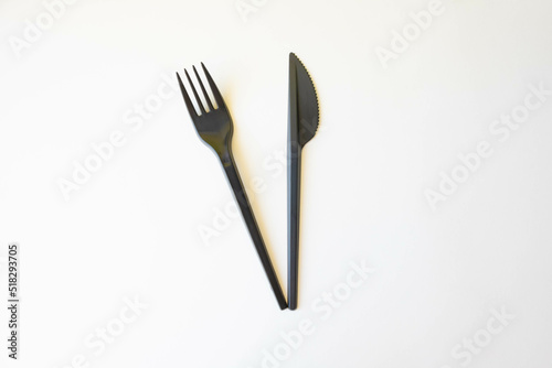 Top view of black plastic disposable fork and knife isolated on white