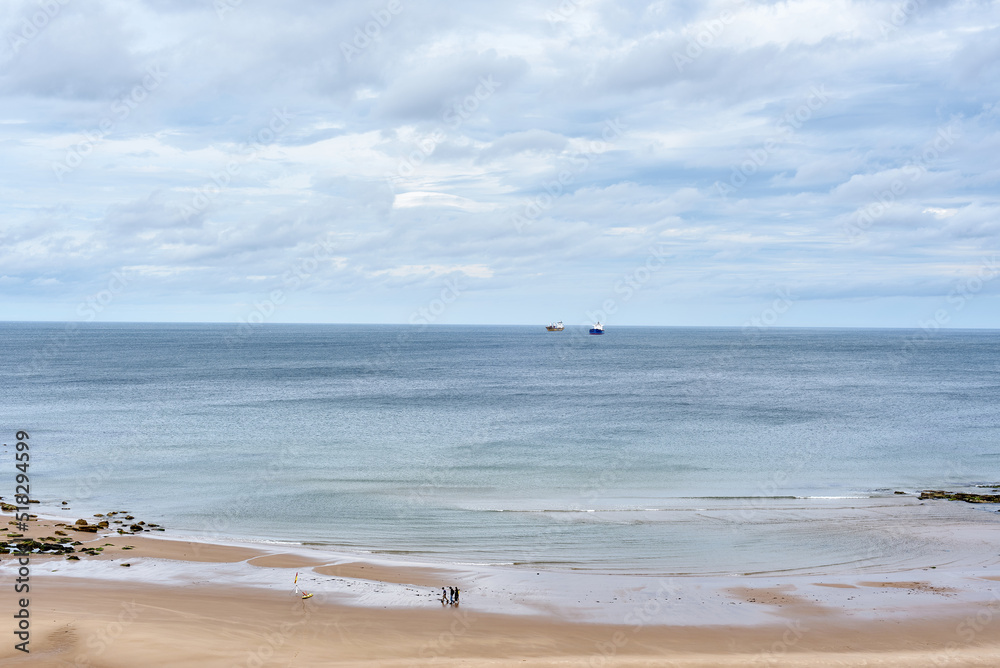 King Edward's Bay beach on the Newcastle coast. A beautiful blue sea stretching into the horizon, over which cloudy dark beautiful clouds hang. Typical English weather. Beautiful sandy beach.