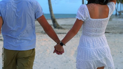 Newlyweds enjoy honeymoon romantic walk on white sand beach. Palm trees. photo