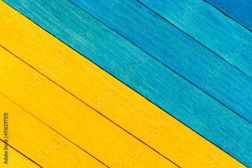 Bicolor wooden textured background in blue and yellow colours. Wooden boards are painted and arranged diagonally. Blue and yellow separated wooden background.